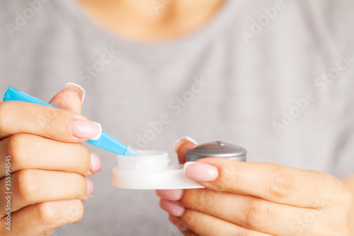 Woman removes contact lenses from a container with liquid