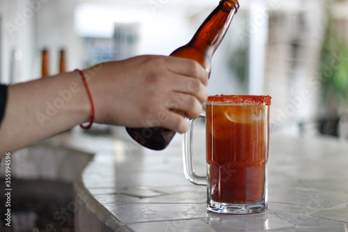 Bartender sirviendo michelada en tarro escarchado  photo