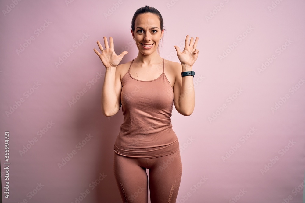 Young blonde fitness woman wearing sport workout clothes over pink isolated background showing and pointing up with fingers number nine while smiling confident and happy. Young blonde fitness woman wearing sport workout clothes over pink isolated background showing and pointing up with fingers number nine while smiling confident and happy.