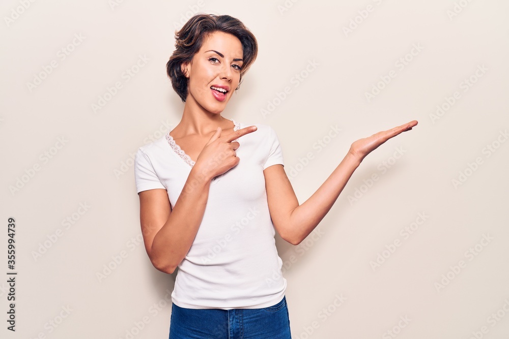 Young beautiful woman wearing casual clothes amazed and smiling to the camera while presenting with hand and pointing with finger. Young beautiful woman wearing casual clothes amazed and smiling to the camera while presenting with hand and pointing with finger.