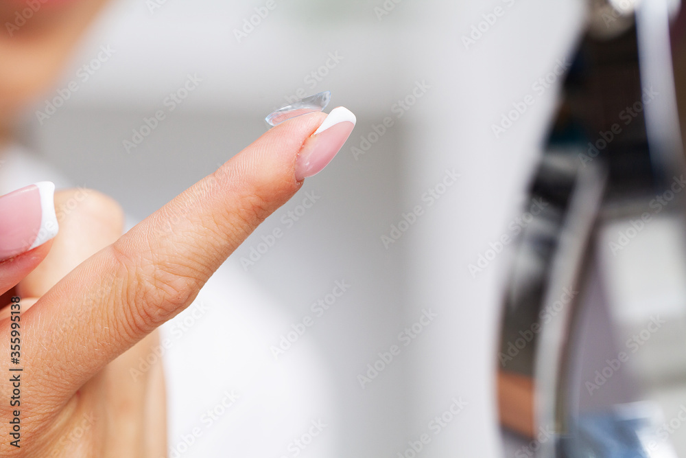 Woman holding a contact lens for eye on her finger