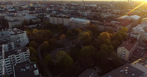 Aerial view around the Koff park in Punavuori district, sunflares, on a sunny morning sunrise, in Helsinki, Finland - Orbit drone shot photo