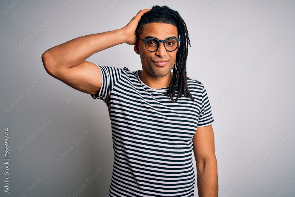 Young handsome african american man with dreadlocks wearing striped t-shirt and glasses confuse and wonder about question. Uncertain with doubt, thinking with hand on head. Pensive concept. Young handsome african american man with dreadlocks wearing striped t-shirt and glasses confuse and wonder about question. Uncertain with doubt, thinking with hand on head. Pensive concept.