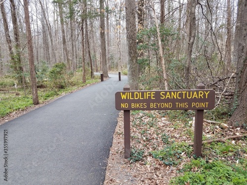 wildlife sanctuary no bikes beyond this point sign and asphalt trail