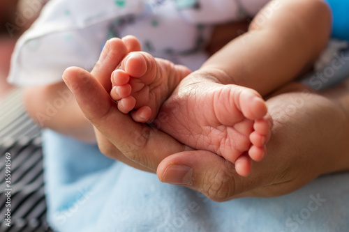 Both feet of a newborn baby child and female hand. © kaentian