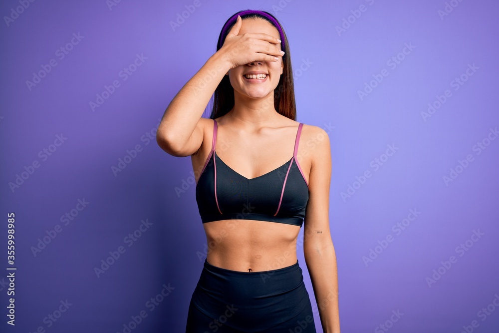 Young beautiful sporty girl doing sport wearing sportswear over isolated purple background smiling and laughing with hand on face covering eyes for surprise. Blind concept. Young beautiful sporty girl doing sport wearing sportswear over isolated purple background smiling and laughing with hand on face covering eyes for surprise. Blind concept.