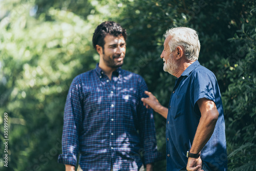 happy an adult hipster son and senior father stay at home, talking in family relationships