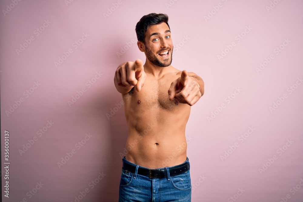 Young handsome strong man with beard shirtless standing over isolated pink background pointing to you and the camera with fingers, smiling positive and cheerful Young handsome strong man with beard shirtless standing over isolated pink background pointing to you and the camera with fingers, smiling positive and cheerful