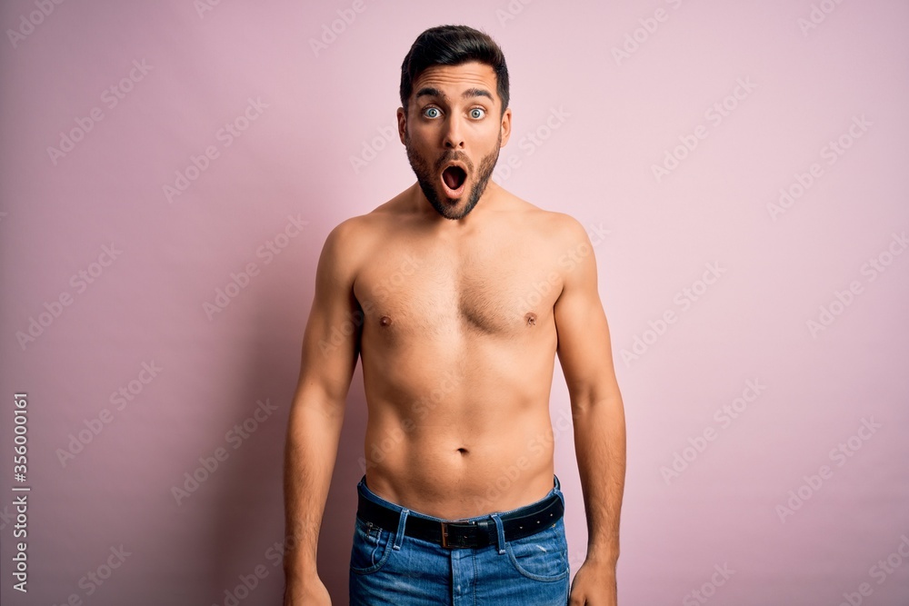 Young handsome strong man with beard shirtless standing over isolated pink background afraid and shocked with surprise and amazed expression, fear and excited face. Young handsome strong man with beard shirtless standing over isolated pink background afraid and shocked with surprise and amazed expression, fear and excited face.
