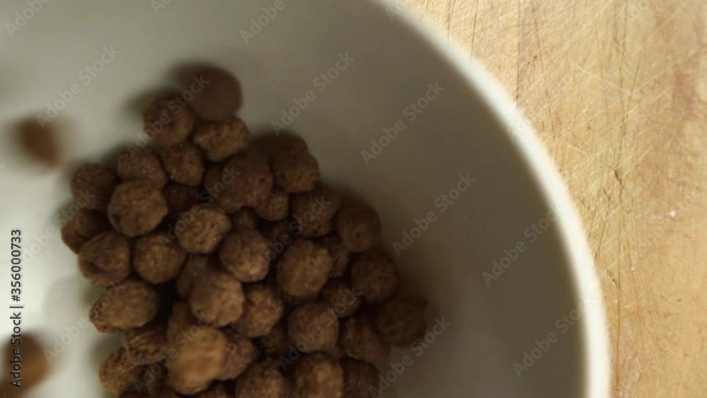 Chocolate corn flakes falling into white bowl. slow motion breakfast. Chocolate corn flakes falling into white bowl. slow motion breakfast.