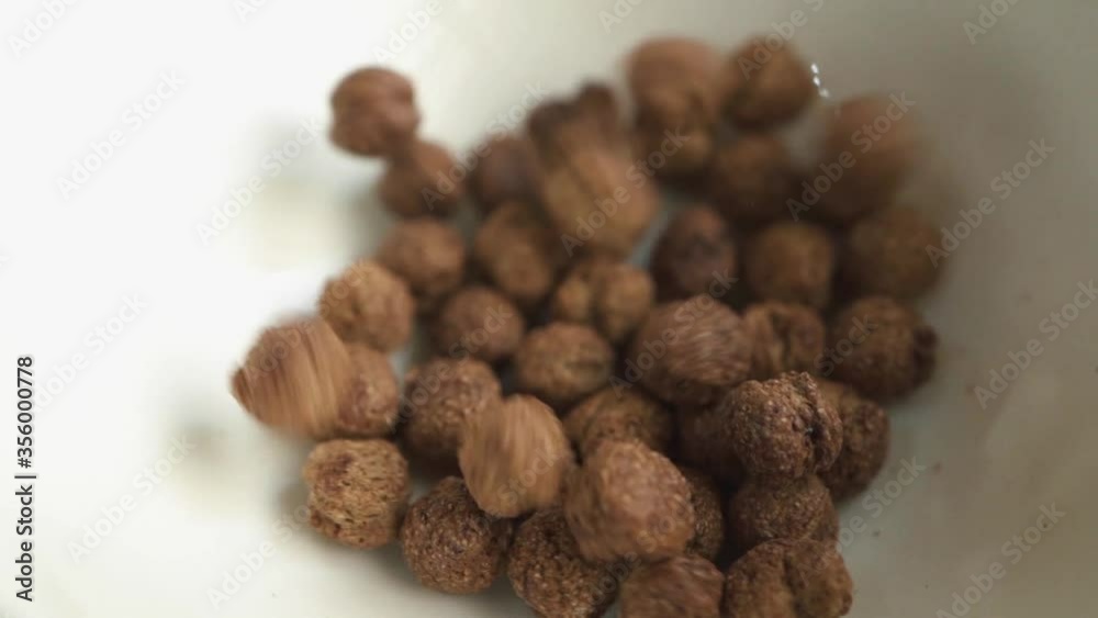 Chocolate corn flakes falling into white bowl. slow motion. breakfast concept. close up Chocolate corn flakes falling into white bowl. slow motion. breakfast concept. close up