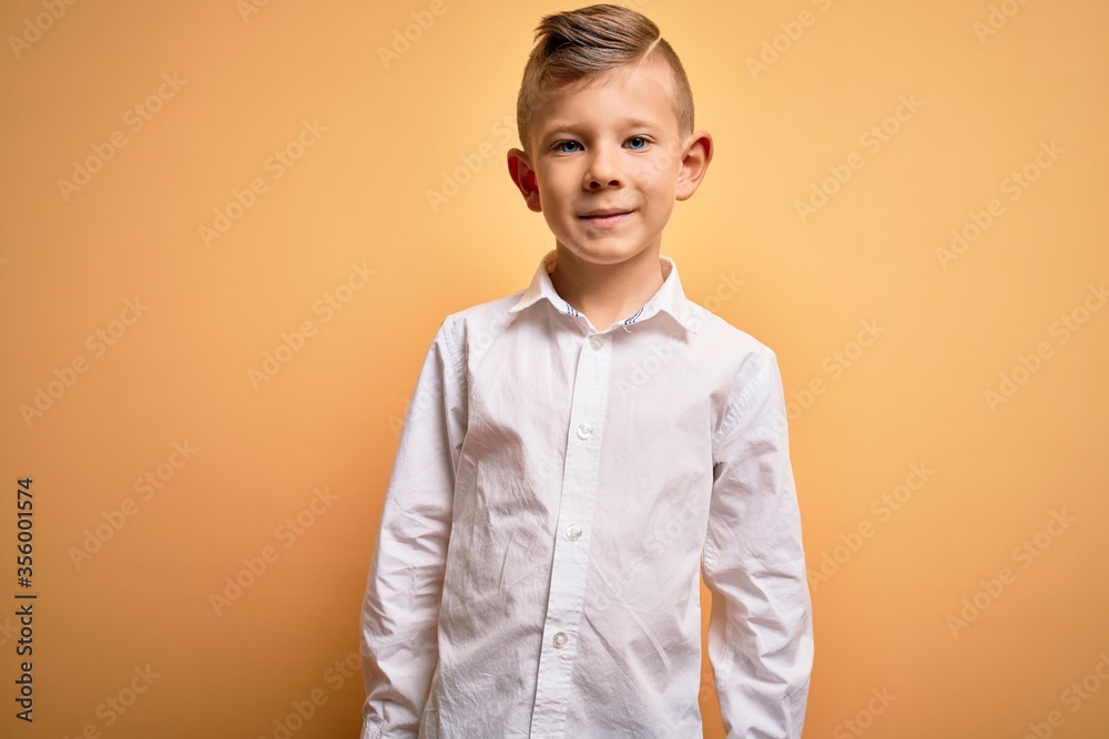 Young little caucasian kid with blue eyes wearing elegant white shirt over yellow background with a happy and cool smile on face. Lucky person. Young little caucasian kid with blue eyes wearing elegant white shirt over yellow background with a happy and cool smile on face. Lucky person.