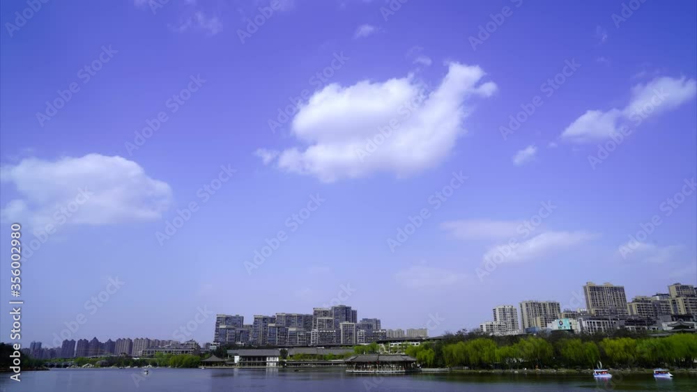 Time-lapse of Chinese coastal city, rolling clouds, tourism boats in park lake Time-lapse of Chinese coastal city, rolling clouds, tourism boats in park lake
