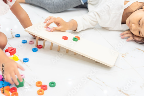 closeup of hand for girl playing color wonder blocks that a geometrical montessori puzzle of colors with constructor on floor at home, family fun at home concept