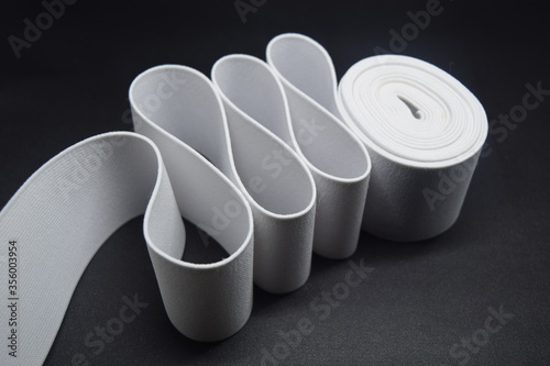 White Knit Elastic Spool for needlework of the cloth insulated on black background. photo