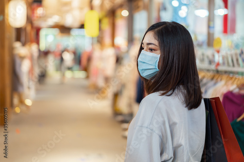 woman shopping with bag at mall and her wearing medical mask for prevention from coronavirus (Covid-19) pandemic. new normal concepts