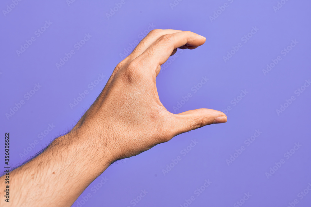 Hand of caucasian young man showing fingers over isolated purple background picking and taking invisible thing, holding object with fingers showing space Hand of caucasian young man showing fingers over isolated purple background picking and taking invisible thing, holding object with fingers showing space