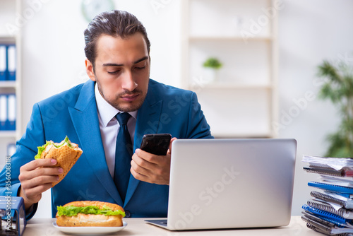 Young male employee having breakfast at workplace