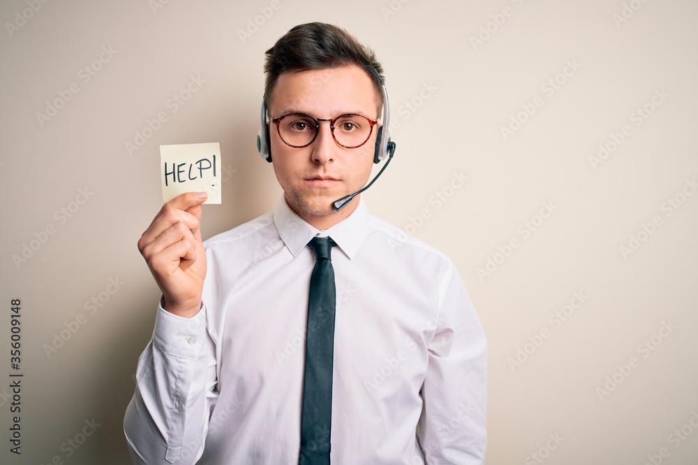 Young call center operator man wearing headset holding paper note with help word with a confident expression on smart face thinking serious Young call center operator man wearing headset holding paper note with help word with a confident expression on smart face thinking serious