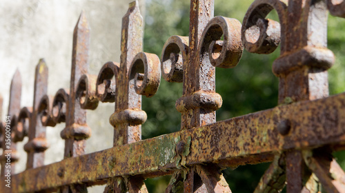 A rusted, decorated, wrought iron fence. Detail of an old retro iron fence made with decorated ironwork elements. Old and worn, still showing some of its former splendor