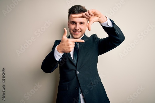 Young handsome business man wearing elegant suit and tie over isolated background smiling making frame with hands and fingers with happy face. Creativity and photography concept.