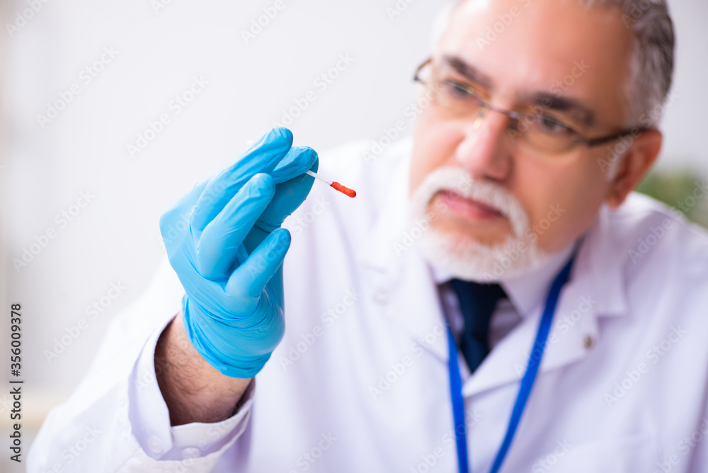 Old male expert criminologist working in the lab for evidence Old male expert criminologist working in the lab for evidence