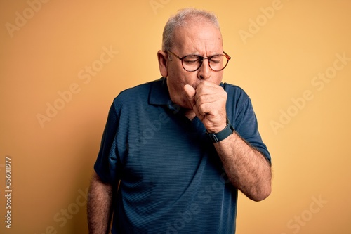 Fotografie Middle age handsome hoary man wearing casual polo and glasses over yellow background feeling unwell and coughing as symptom for cold or bronchitis