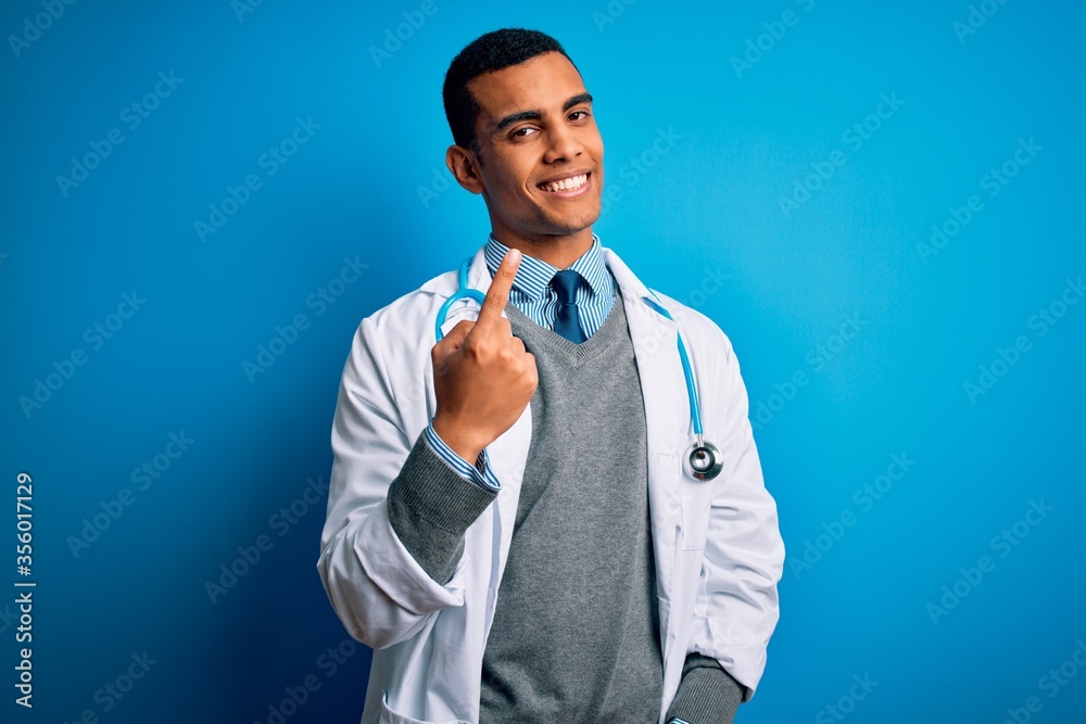 Handsome african american doctor man wearing coat and stethoscope over blue background Beckoning come here gesture with hand inviting welcoming happy and smiling Handsome african american doctor man wearing coat and stethoscope over blue background Beckoning come here gesture with hand inviting welcoming happy and smiling