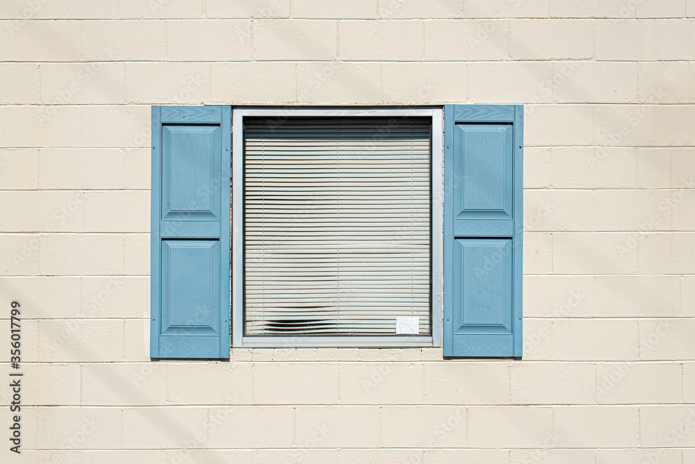 Window with blue shutters opened on a white wall