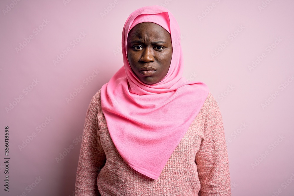 Young african american plus size woman wearing muslim hijab over isolated pink background skeptic and nervous, frowning upset because of problem. Negative person. Young african american plus size woman wearing muslim hijab over isolated pink background skeptic and nervous, frowning upset because of problem. Negative person.