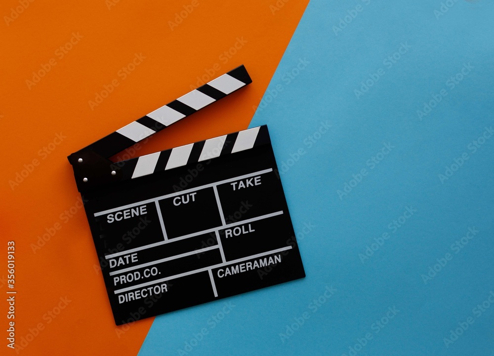 Filmmaking concept. Movie Clapperboard. Cinema begins with movie clappers. Movie clapper on an orange and a blue background.