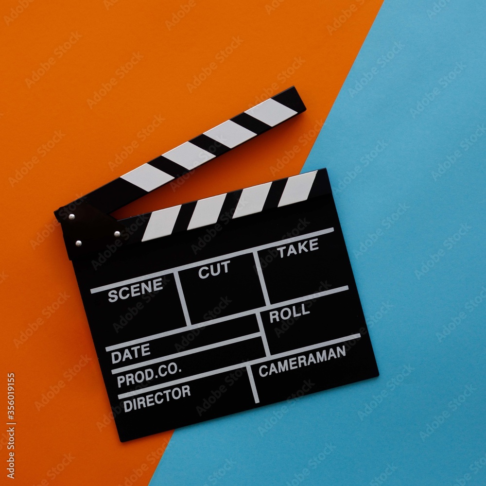 Filmmaking concept. Movie Clapperboard. Cinema begins with movie clappers. Movie clapper on an orange and a blue background. Square.
