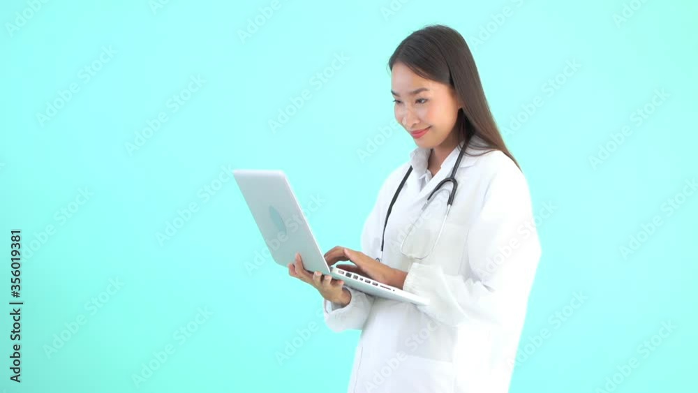 A young female healthcare professional holds a laptop in one hand and enters data with other, copy space. A young female healthcare professional holds a laptop in one hand and enters data with other, copy space.