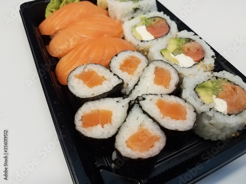 orange salmon sushi with rice in black plastic tray