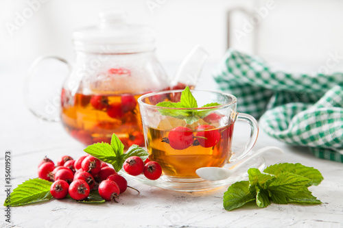 tea with a hawthorn and mint in a cup on a table, selective focus photo