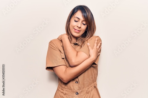 Young beautiful woman wearing casual dress hugging oneself happy and positive, smiling confident. self love and self care