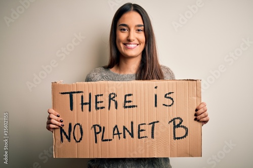 Young beautiful brunette activist woman protesting for save the planet holding banner with a happy face standing and smiling with a confident smile showing teeth © Krakenimages.com