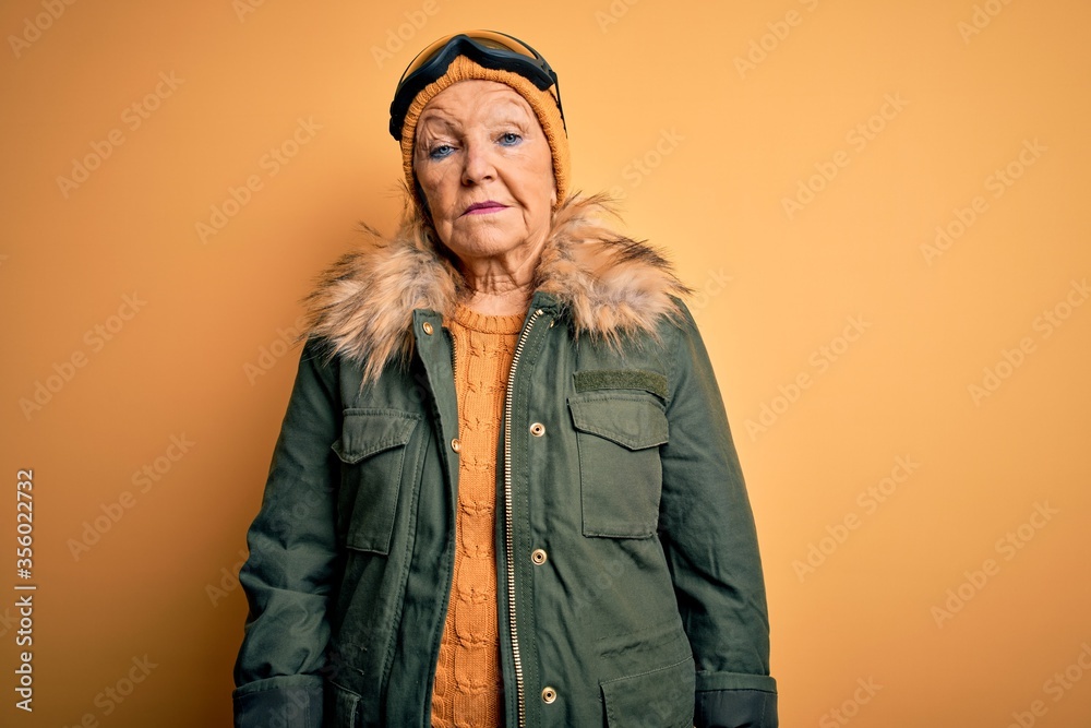 Senior beautiful grey-haired skier woman wearing snow sportswear and ski goggles Relaxed with serious expression on face. Simple and natural looking at the camera. Senior beautiful grey-haired skier woman wearing snow sportswear and ski goggles Relaxed with serious expression on face. Simple and natural looking at the camera.