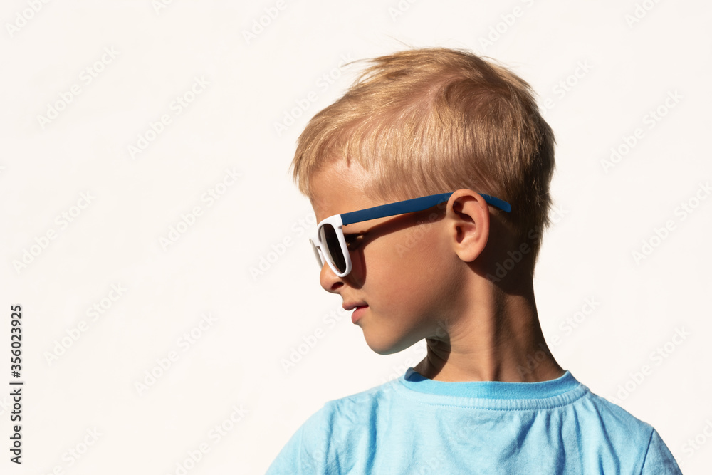 Portrait of a beautiful boy in fashionable dark glasses and a blue t-shirt on a white background Portrait of a beautiful boy in fashionable dark glasses and a blue t-shirt on a white background