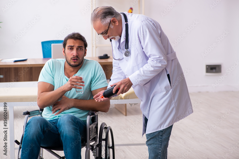 Experienced doctor and young male patient in wheel-chair
