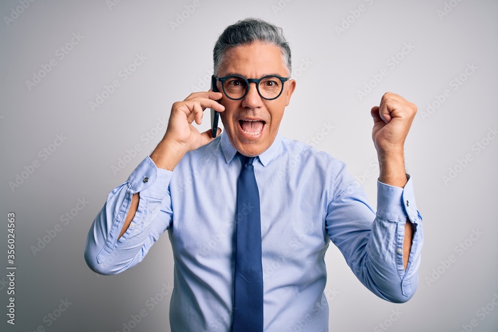 Middle age handsome grey-haired business man having conversation talking on the smartphone screaming proud and celebrating victory and success very excited, cheering emotion Middle age handsome grey-haired business man having conversation talking on the smartphone screaming proud and celebrating victory and success very excited, cheering emotion