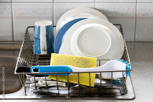 White & blue crockery & utensils drying in wire rack.