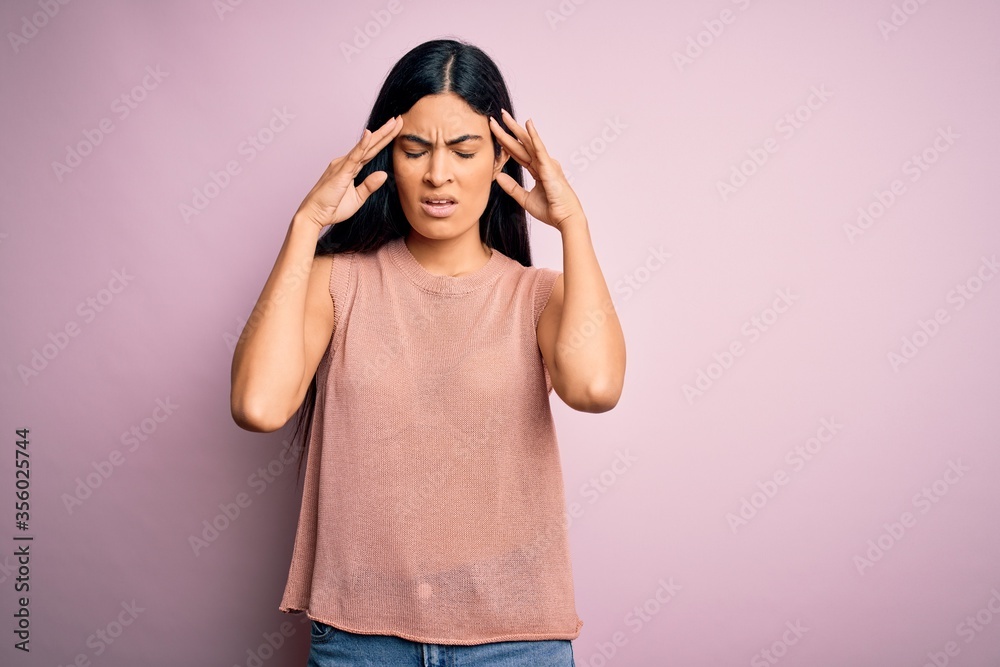 Young beautiful hispanic fashion woman wearing casual sweater over pink background suffering from headache desperate and stressed because pain and migraine. Hands on head. Young beautiful hispanic fashion woman wearing casual sweater over pink background suffering from headache desperate and stressed because pain and migraine. Hands on head.