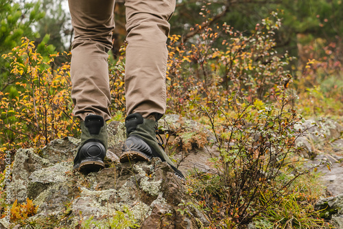 Hiking boots on rock. Men's feet in boots on natural stones. Travel and adventure concept