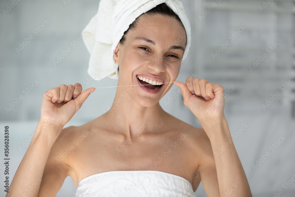Head shot portrait beautiful woman with healthy toothy smile using mint dental floss, removing food cleaning teeth, pretty girl wearing white bath towel on head looking at camera, personal hygiene Head shot portrait beautiful woman with healthy toothy smile using mint dental floss, removing food cleaning teeth, pretty girl wearing white bath towel on head looking at camera, personal hygiene