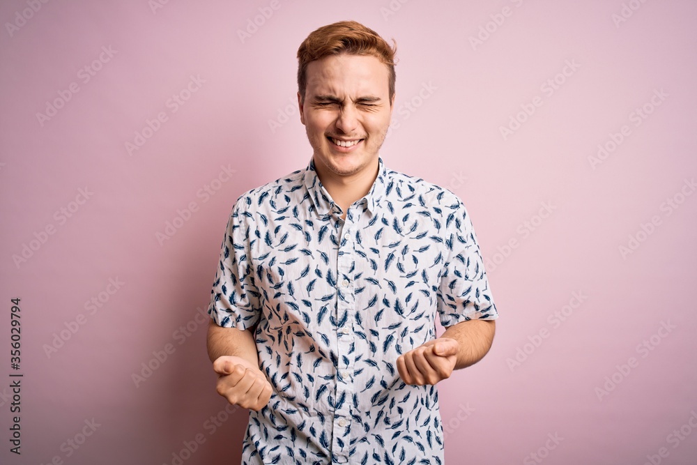 Young handsome redhead man wearing casual summer shirt standing over pink background very happy and excited doing winner gesture with arms raised, smiling and screaming for success. Celebration Young handsome redhead man wearing casual summer shirt standing over pink background very happy and excited doing winner gesture with arms raised, smiling and screaming for success. Celebration