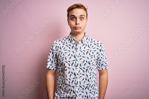Wallpaper Mural Young handsome redhead man wearing casual summer shirt standing over pink background puffing cheeks with funny face. Mouth inflated with air, crazy expression. Torontodigital.ca