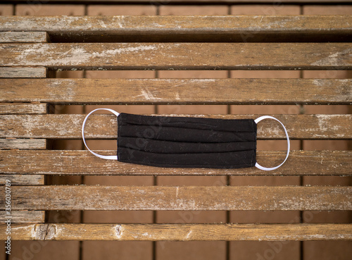 DIY handmade cotton face mask sitting on a wooden bench. Homemade COVID-19 protection 