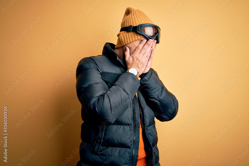 Young handsome skier man skiing wearing snow sportswear using ski goggles with sad expression covering face with hands while crying. Depression concept. Young handsome skier man skiing wearing snow sportswear using ski goggles with sad expression covering face with hands while crying. Depression concept.