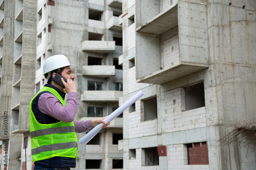 Young Engineer Working on Building Site  and giving Tasks over the Phone